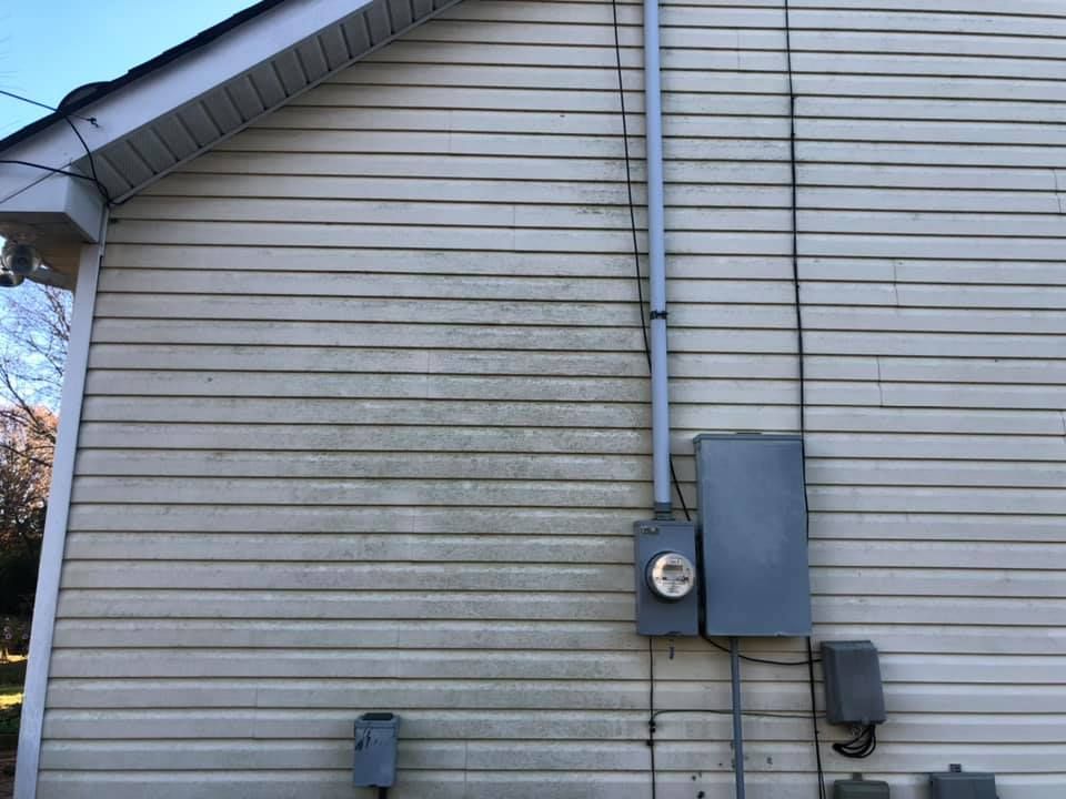 Side of a beige house with a utility meter and electrical boxes mounted on the wall.