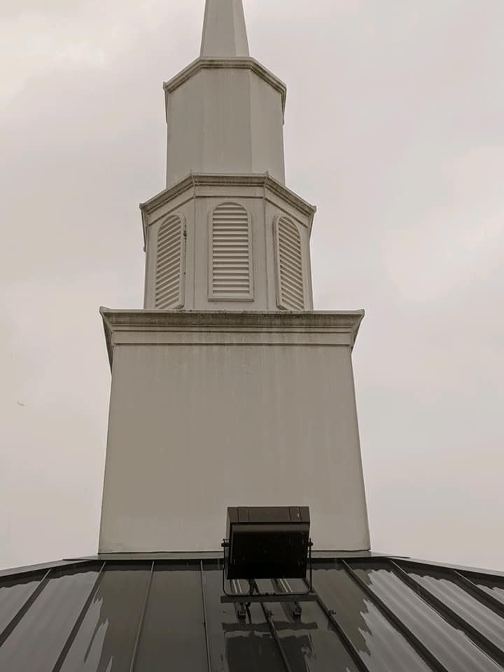 White church steeple against a cloudy sky, viewed from below.