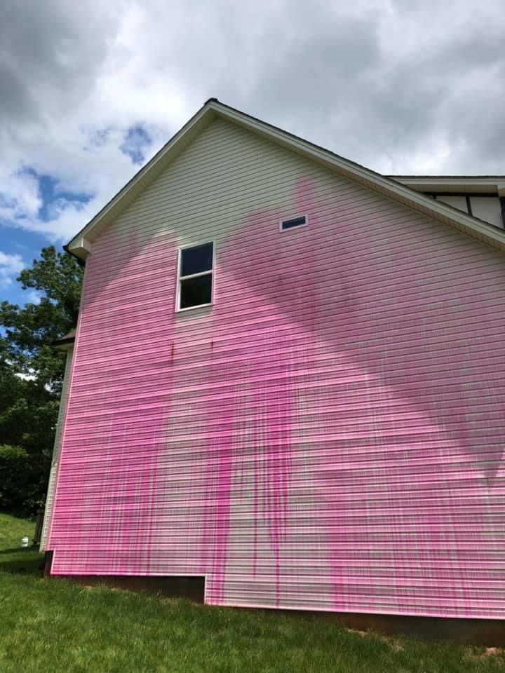 Pink-sided house with white trim and a small window under a cloudy sky