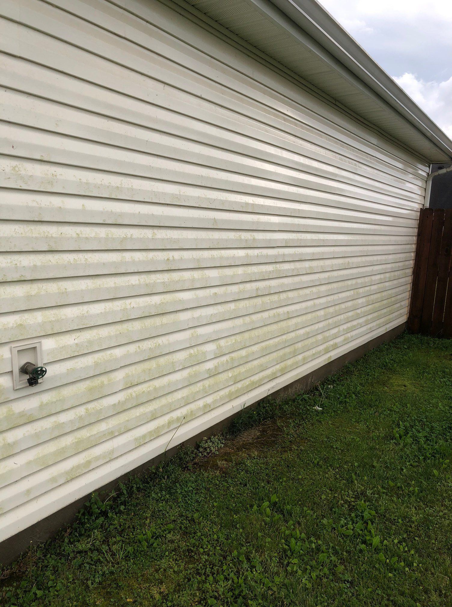 White vinyl house siding beside a grassy yard, with a fence at the far end.