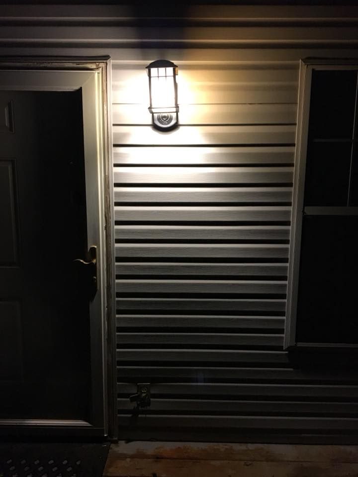 Front door with porch light illuminating beige siding at night