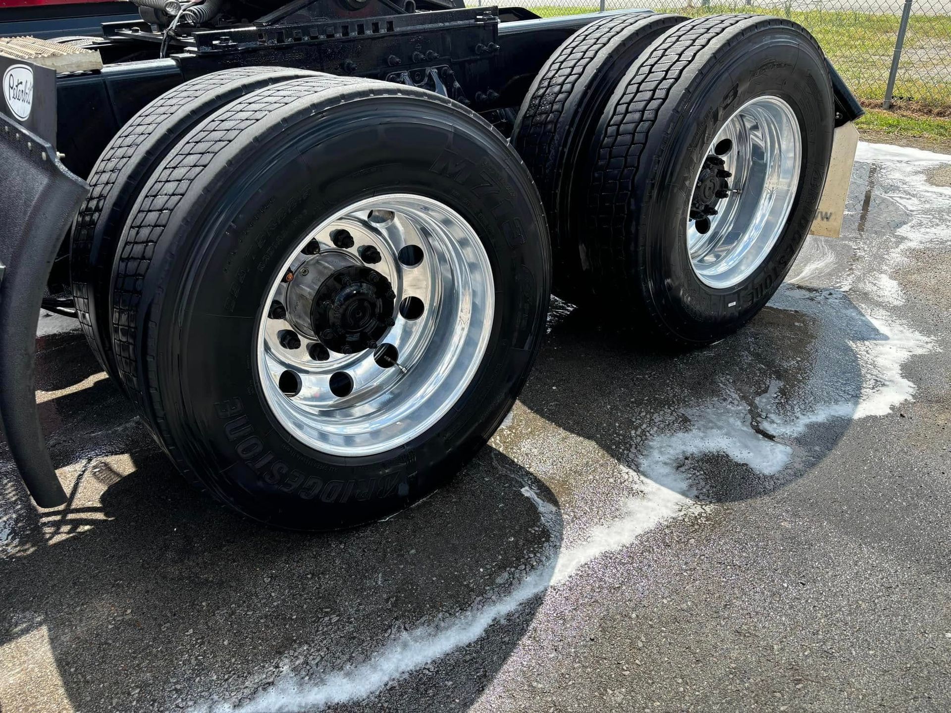 Close-up of dual truck tires and wheels on a wet road with white lines, parked by a curb