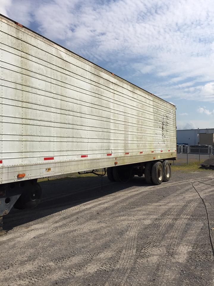 White semi-trailer truck parked on a gravel lot under a partly cloudy sky