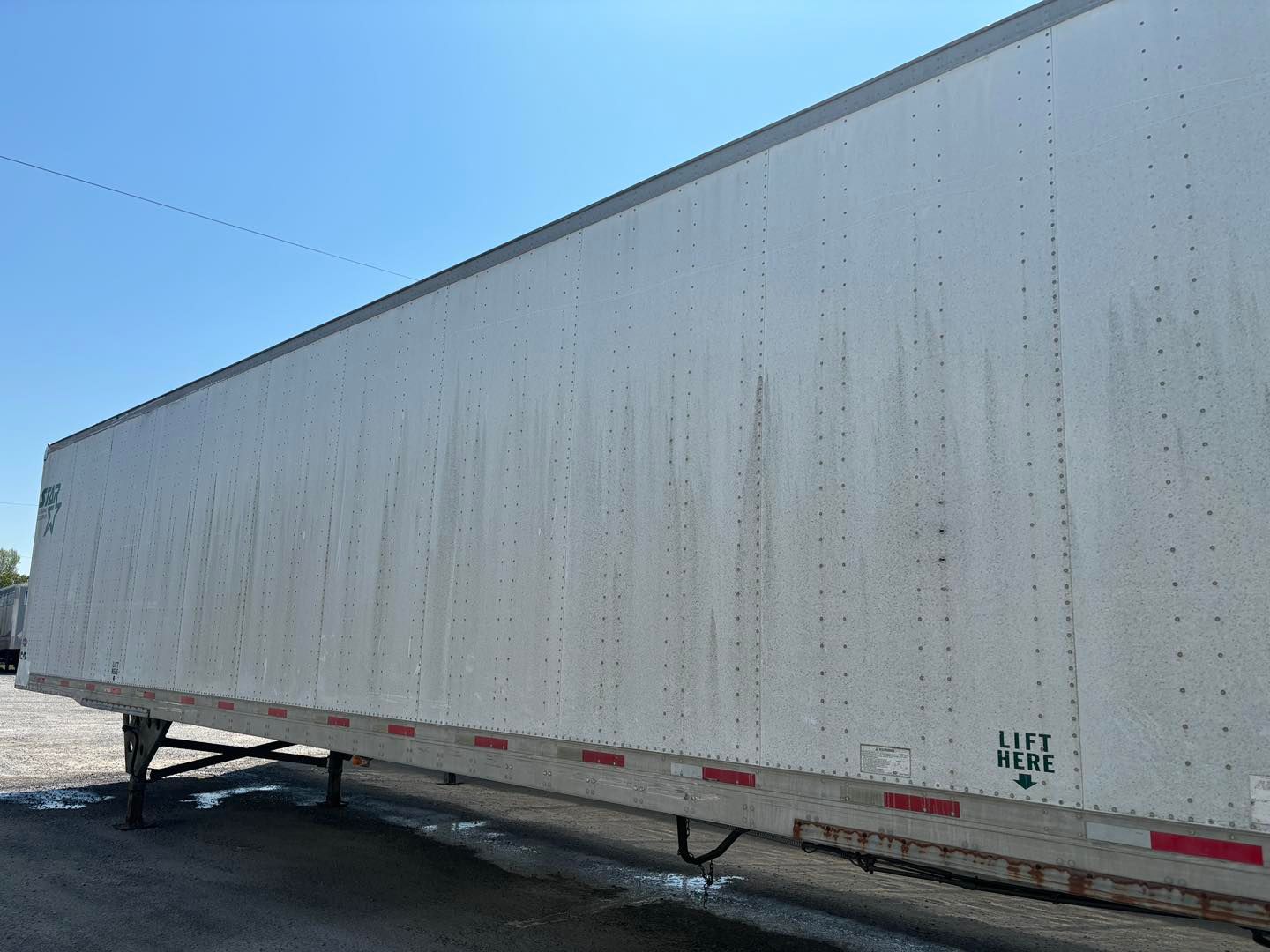 White semi-trailer parked on a lot under a clear blue sky