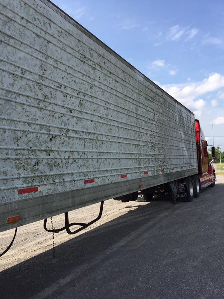 Long silver semi-trailer on a road, with a red cab visible at the front.