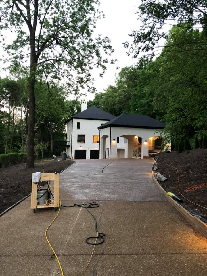 New home exterior at dusk with lit porch, driveway, and construction equipment in front