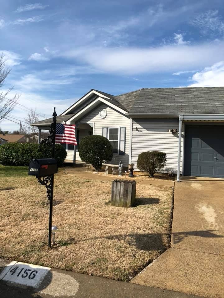 Suburban house with an American flag, mailbox, and front yard under a blue sky.