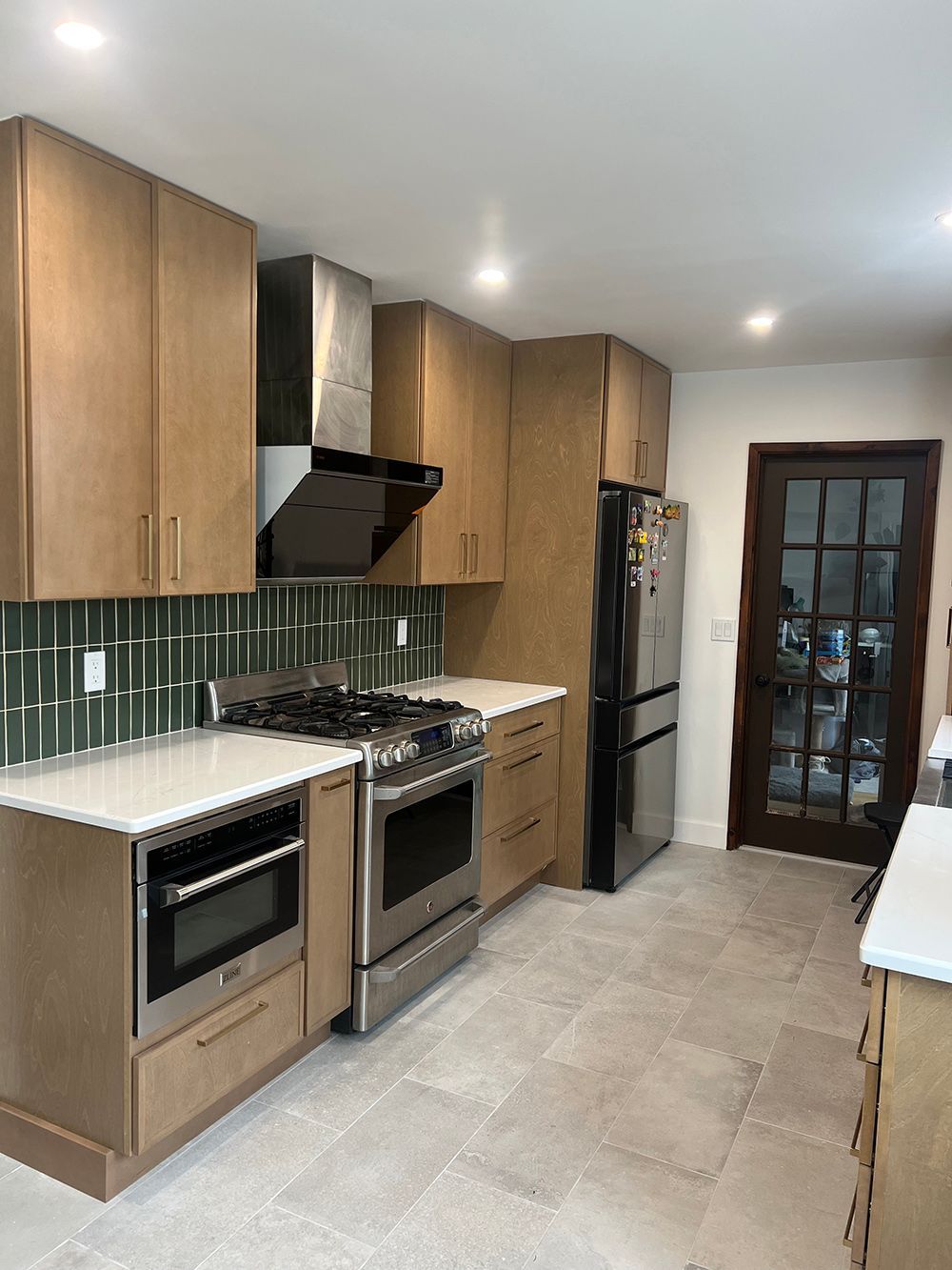 Modern kitchen with wood cabinets, stainless steel appliances, white countertops, and tiled floor