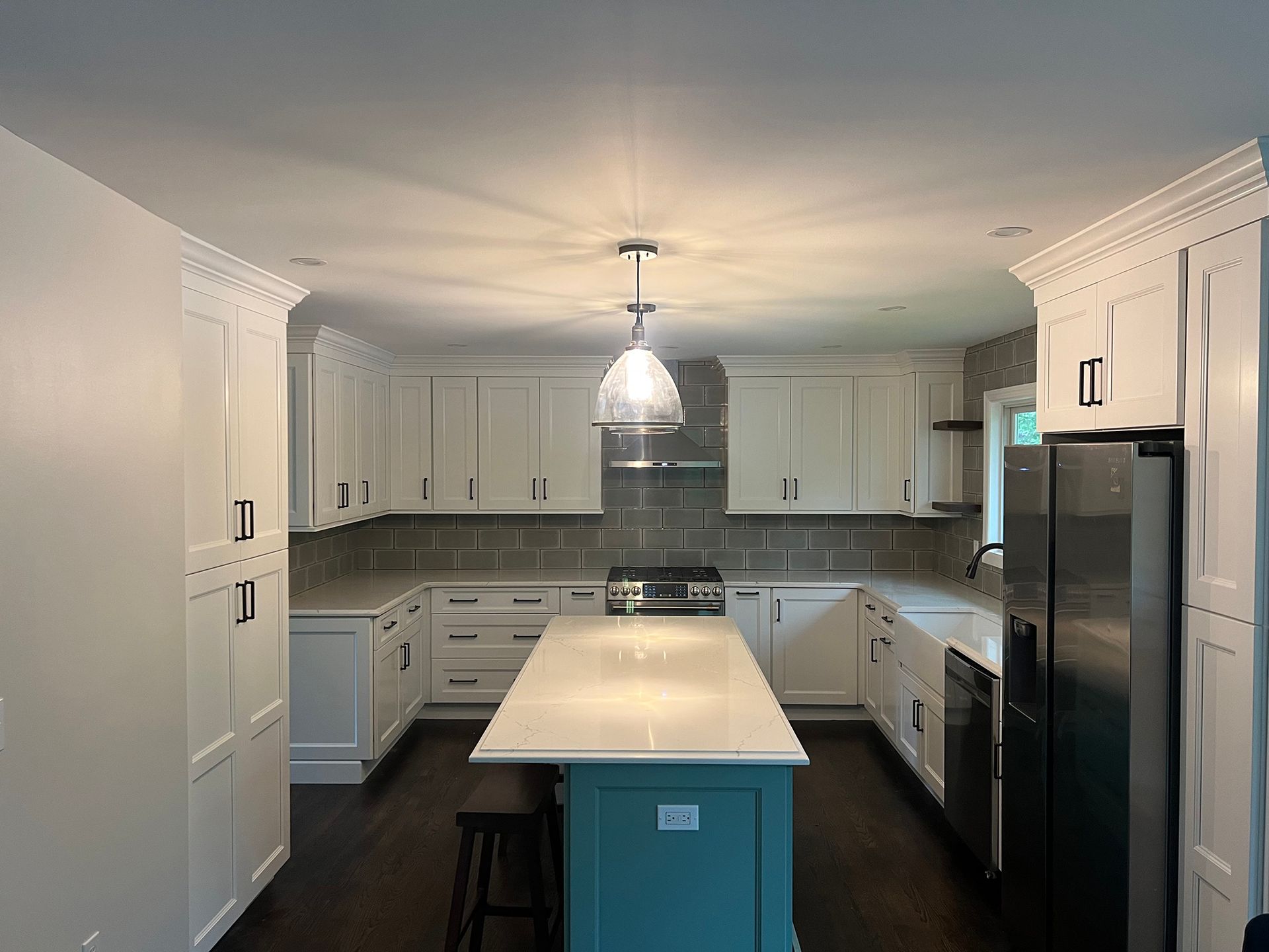 Bright modern kitchen with white cabinets, dark floor, central island, and stainless steel appliances