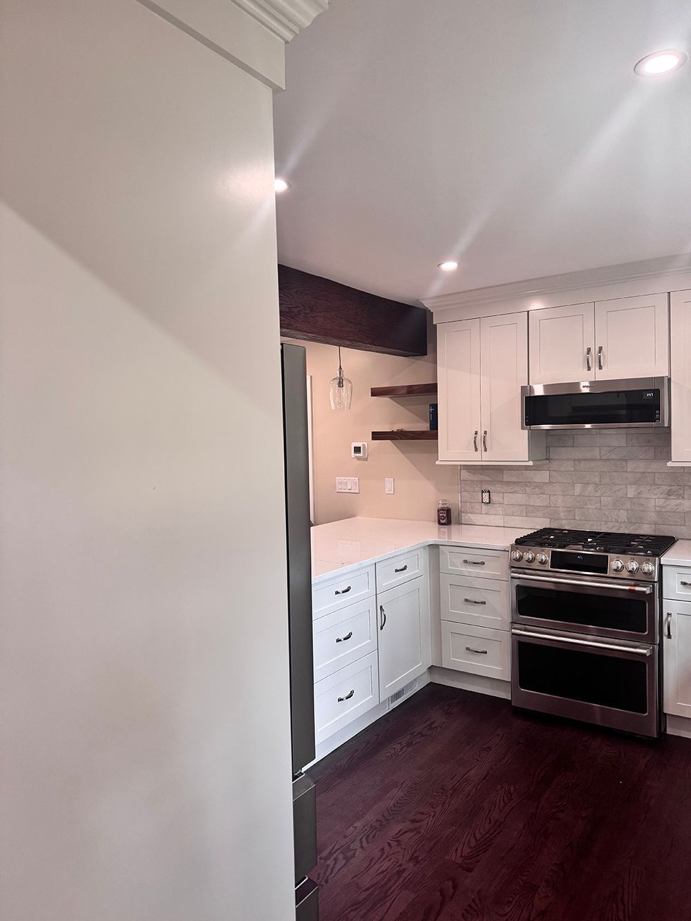 Bright modern kitchen with white cabinets, stainless steel stove, and dark hardwood floors
