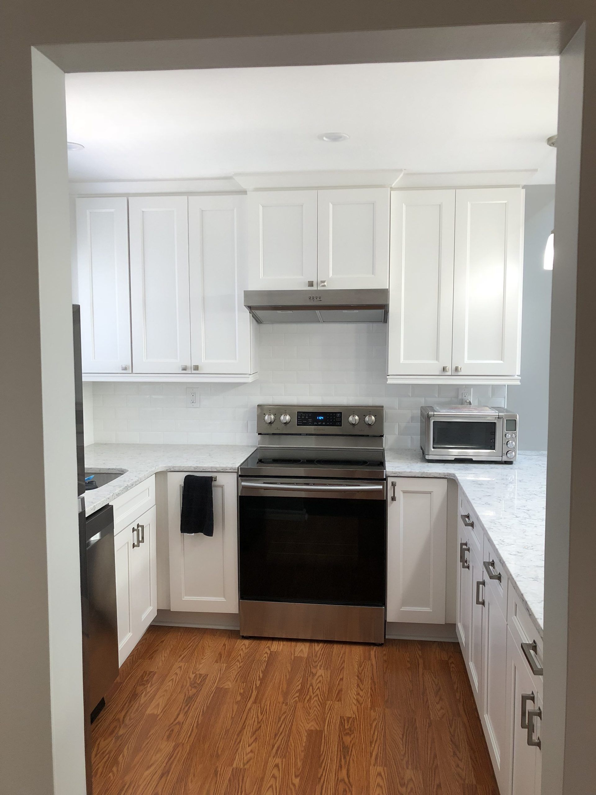 White kitchen with cabinets, refrigerator, and a doorway to stairs.