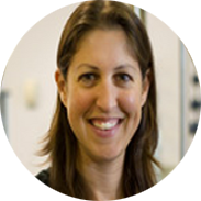 Woman with brown hair smiling; neutral background.