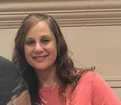 Woman with brown hair smiling indoors.