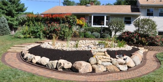 A garden with rocks and plants in front of a house.