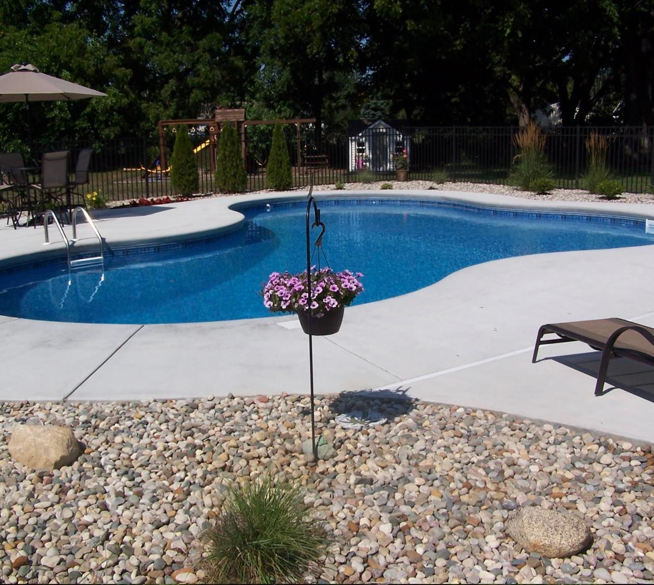 A large swimming pool surrounded by rocks and flowers