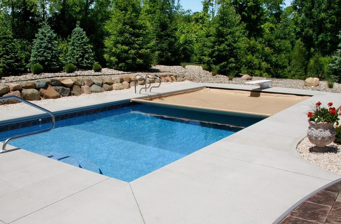 A large swimming pool is surrounded by a concrete patio.