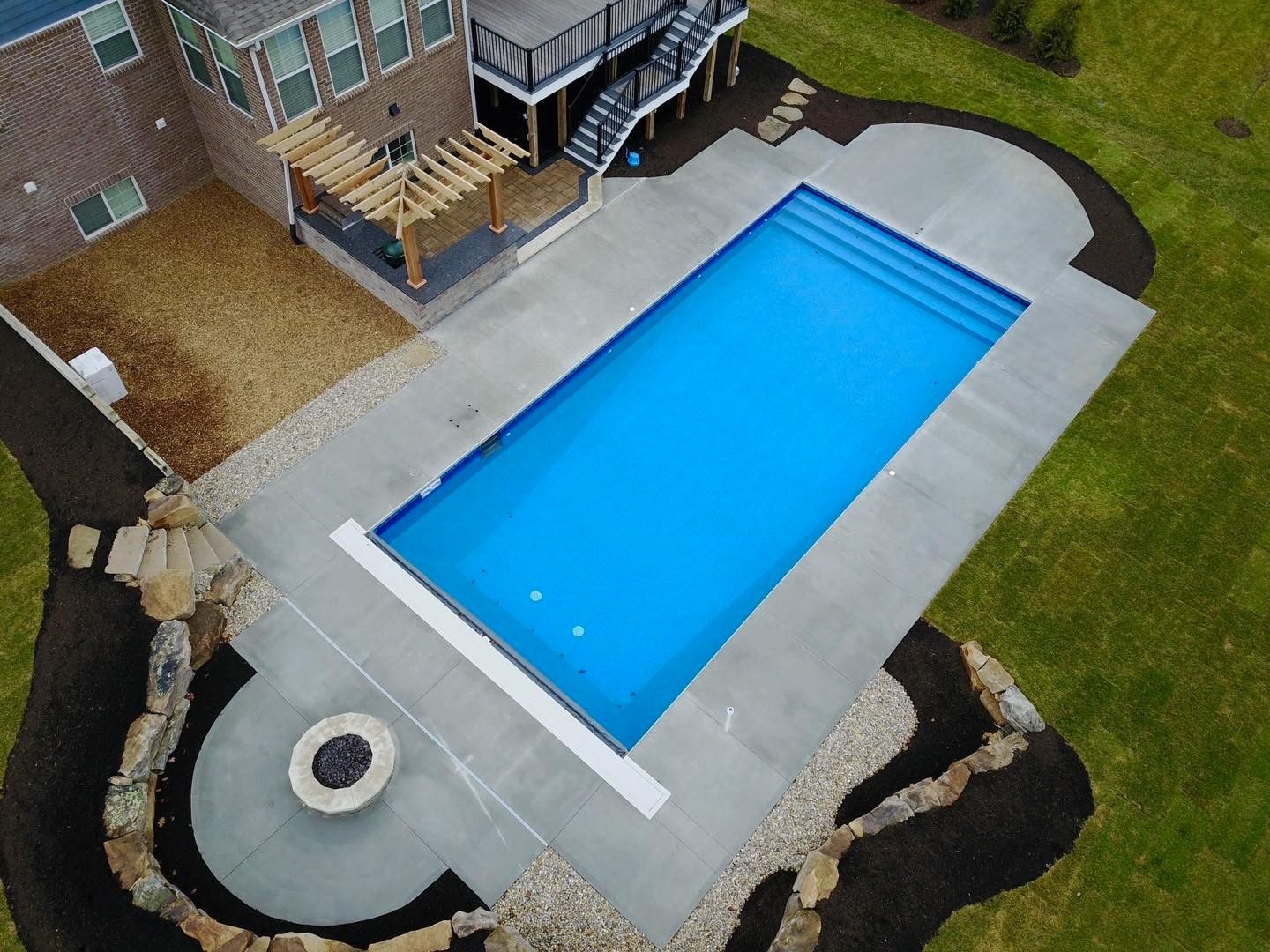 An aerial view of a large swimming pool in the backyard of a house
