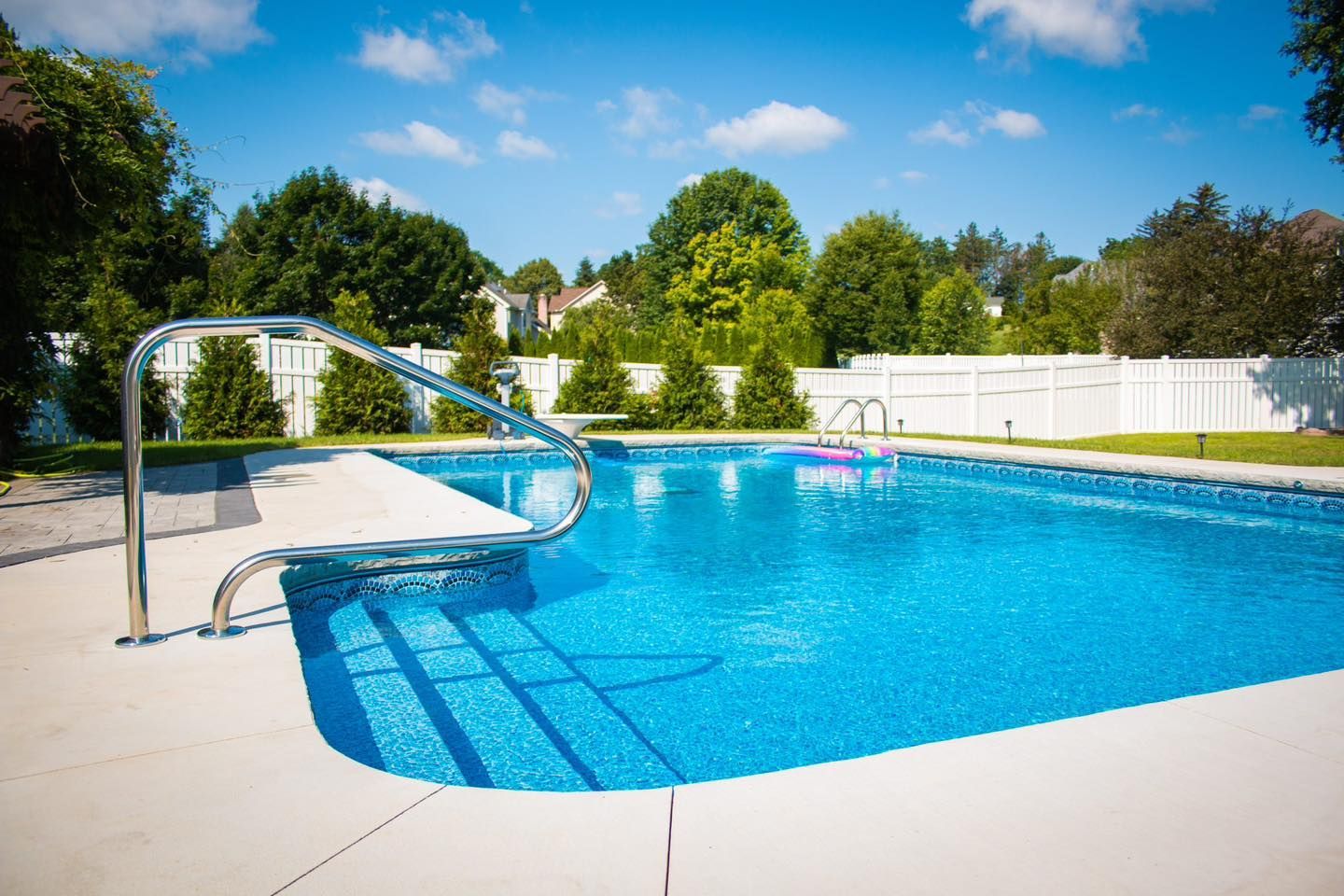 A large swimming pool with stairs leading to it in a backyard.