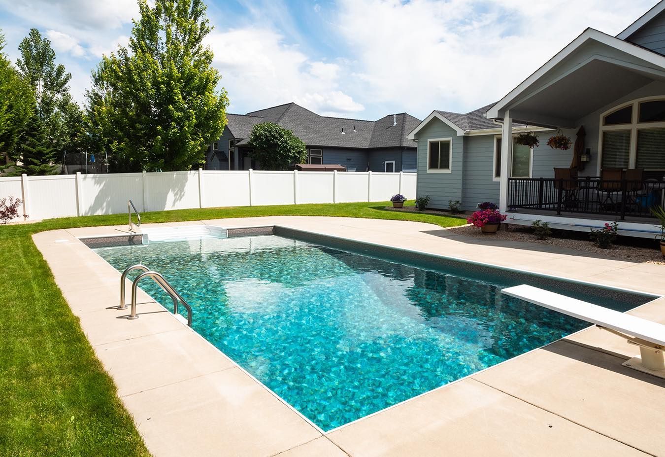 There is a large swimming pool in the backyard of a house.