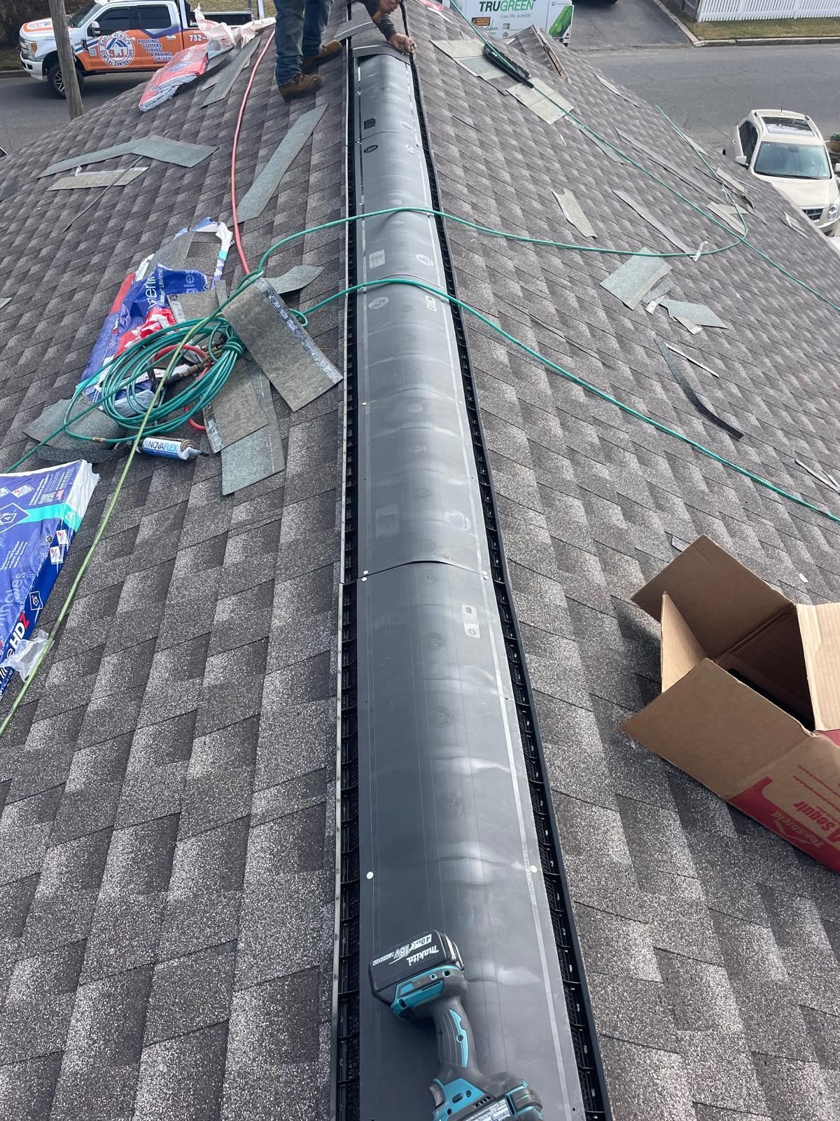 A man is working on a roof with a drill.