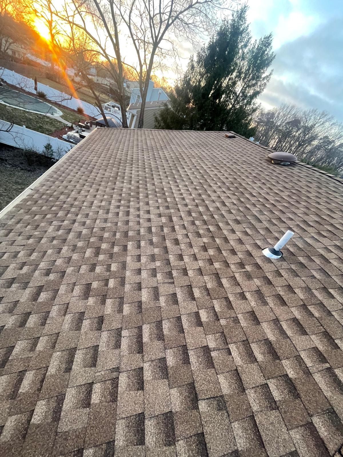 A close up of a roof with a sunset in the background.