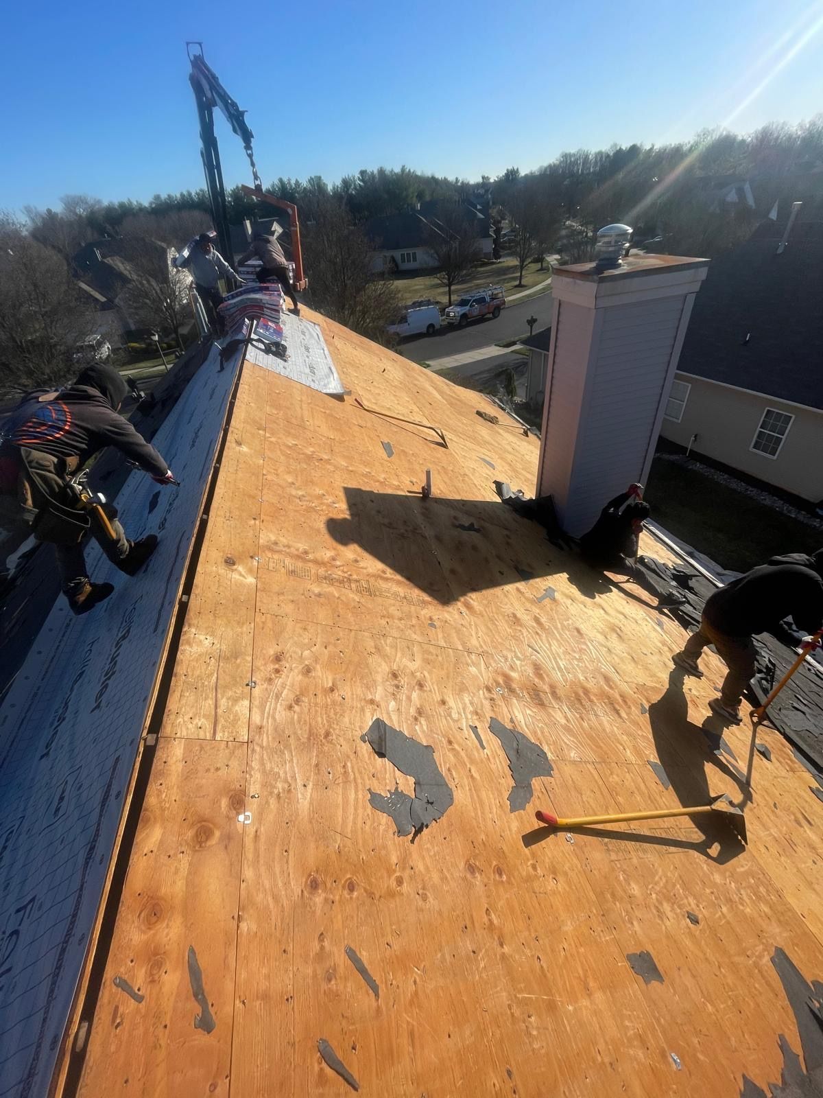 A group of people are working on the roof of a house.