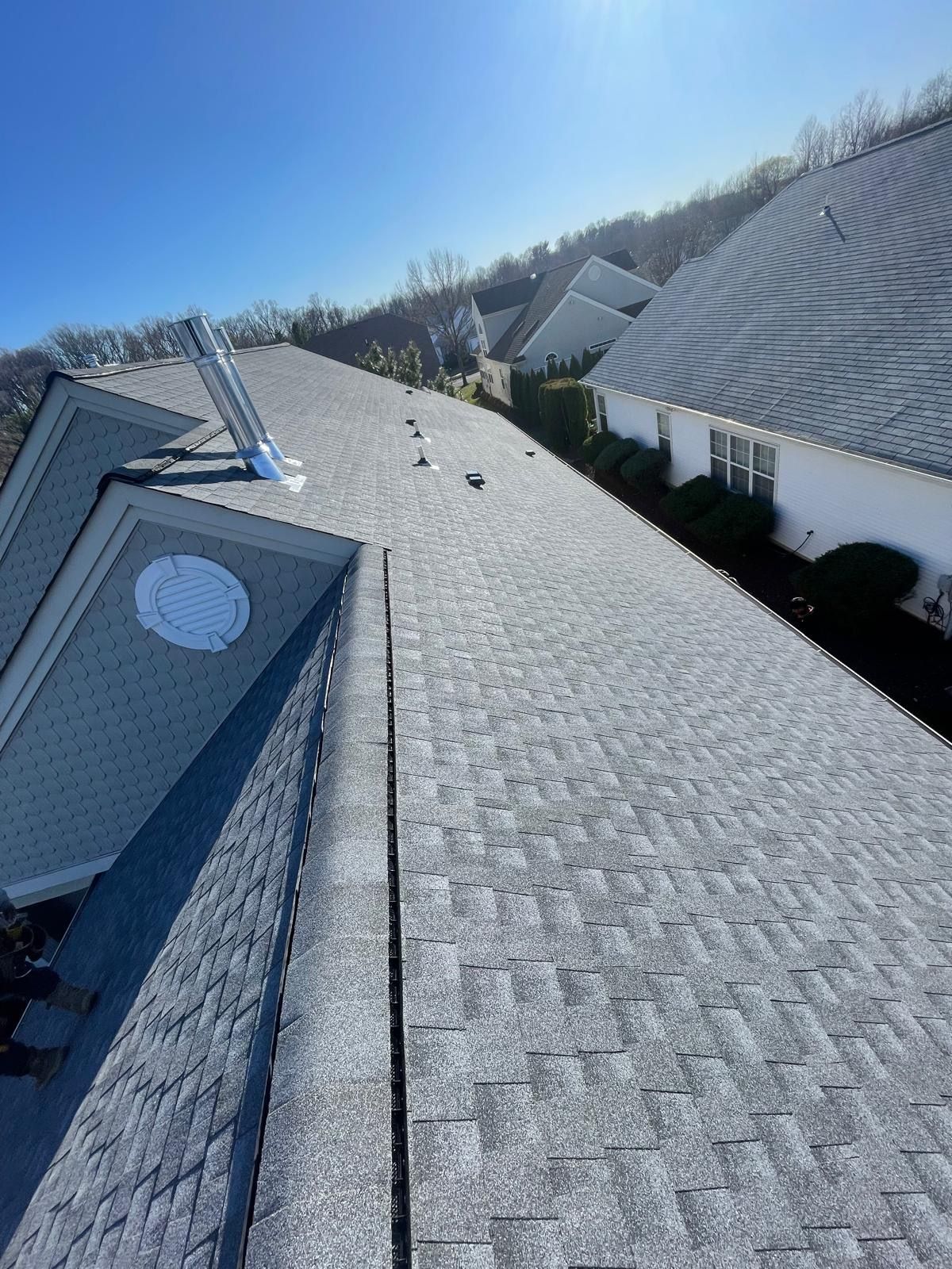 A roof with a lot of shingles and a skylight on it.