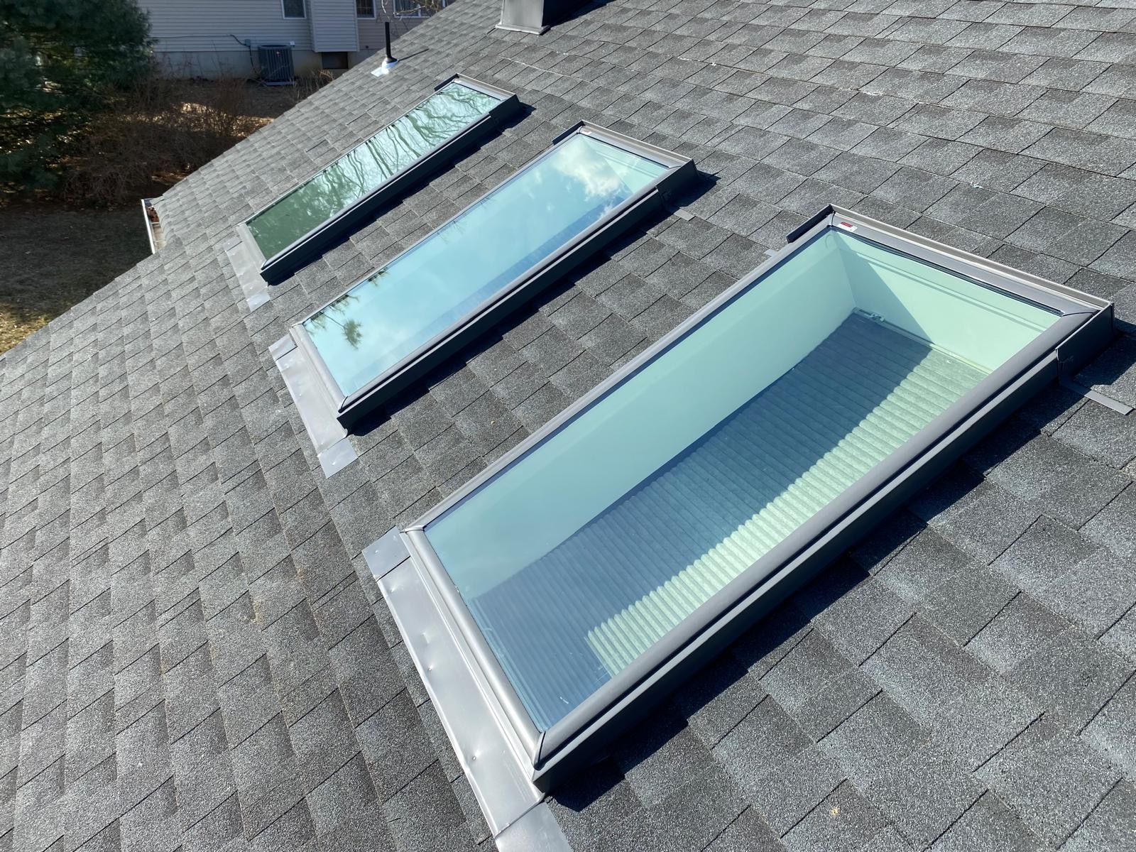 A group of men are working on a roof with skylights.