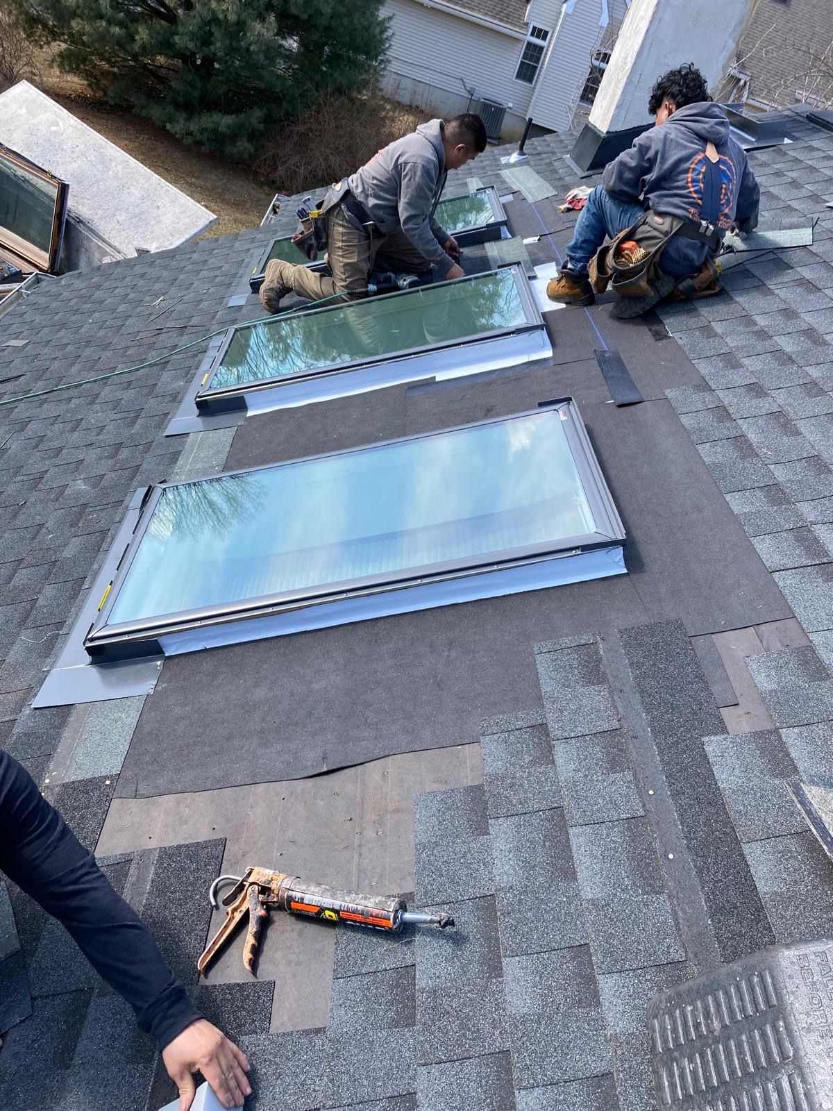 A group of men are working on a roof with skylights.