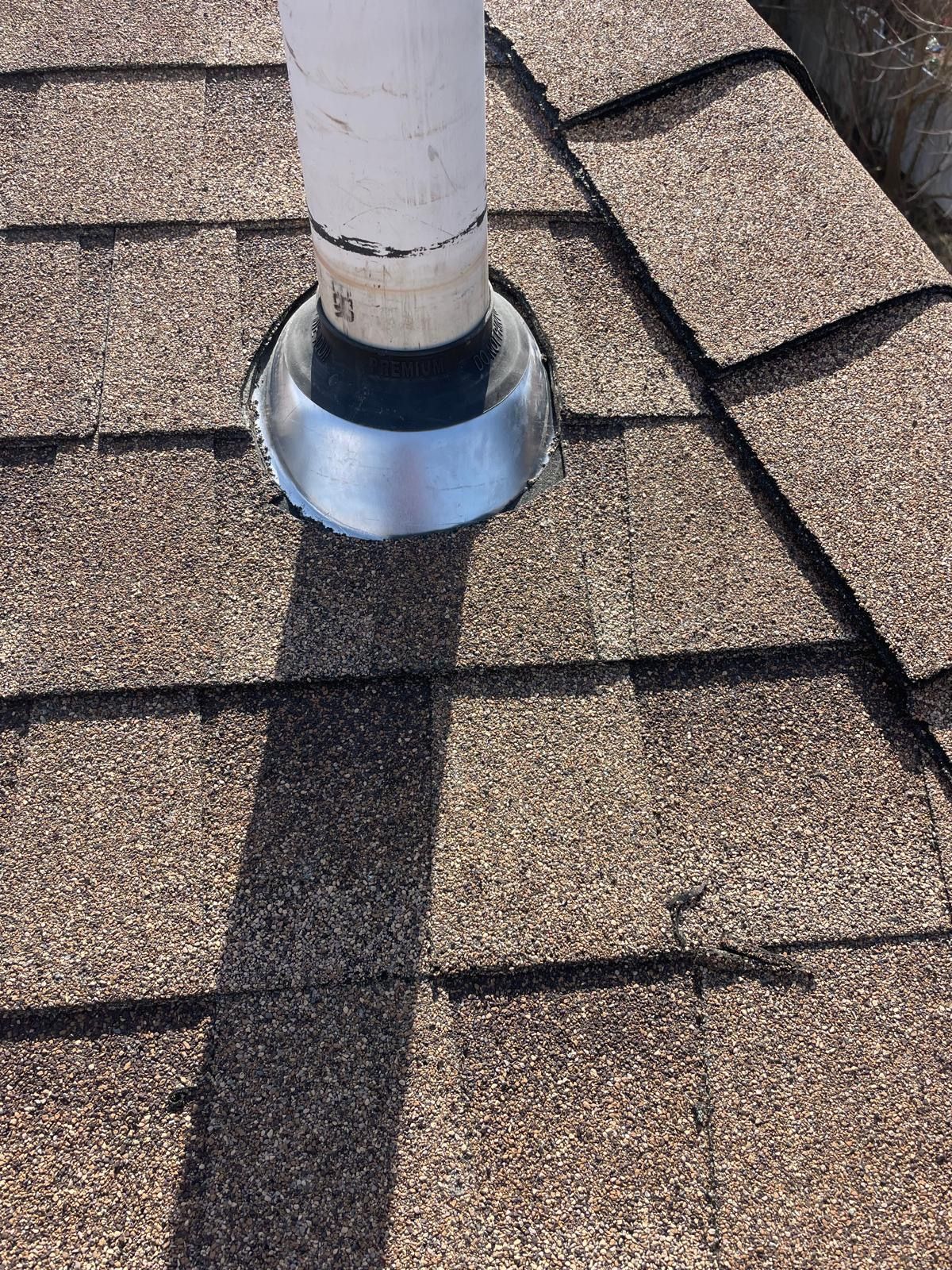A pipe is sitting on top of a roof with shingles.