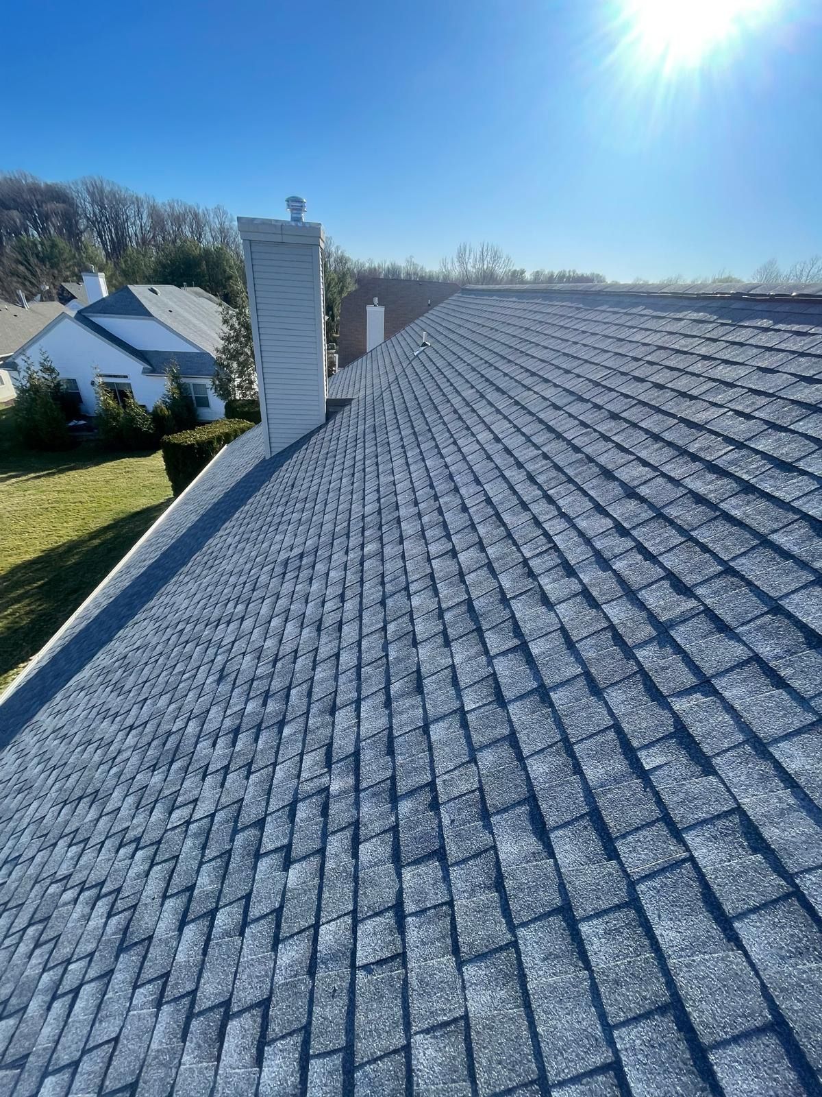 A close up of a roof with a chimney on a sunny day.