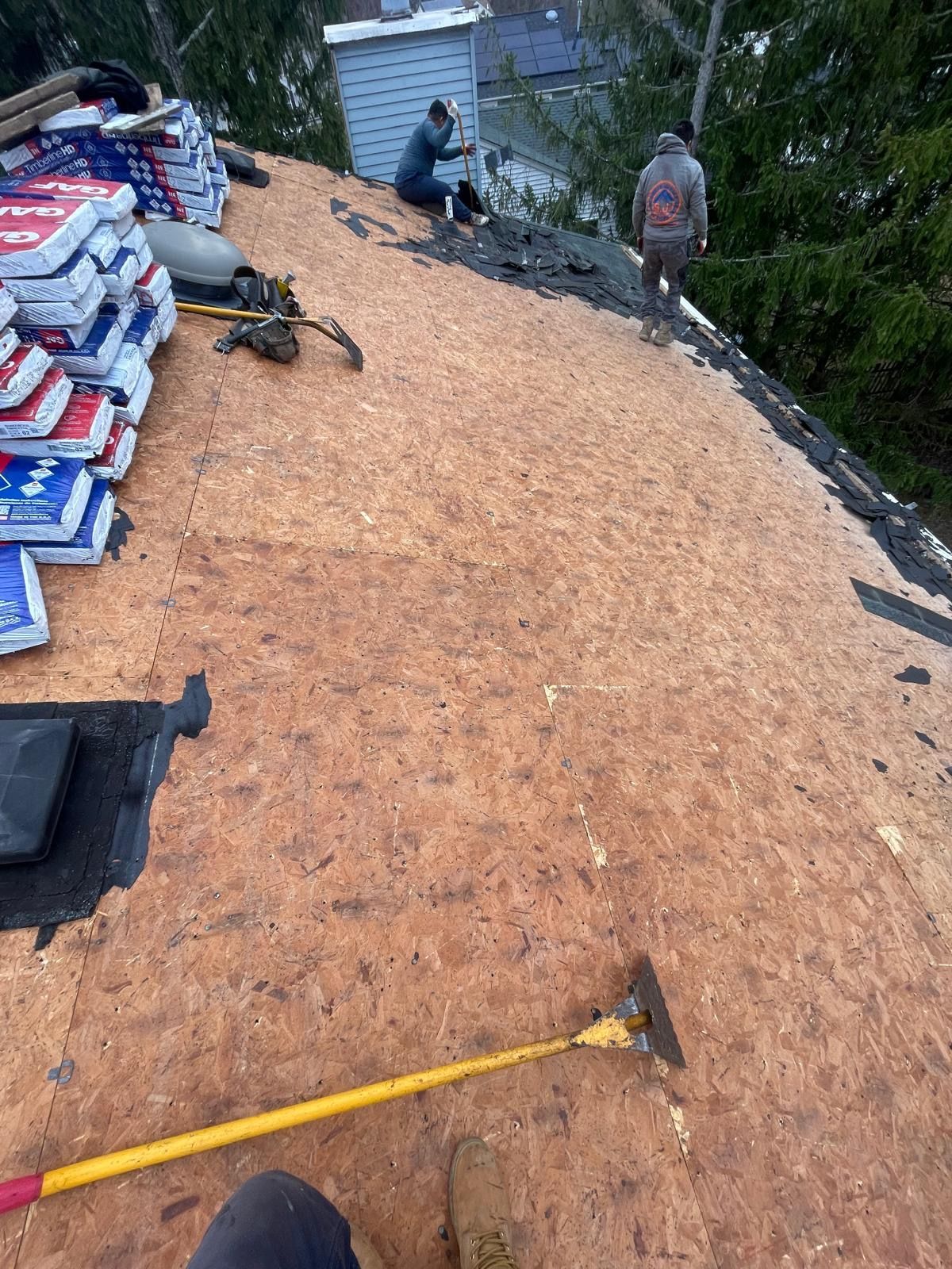 A person is standing on top of a roof with a rake.