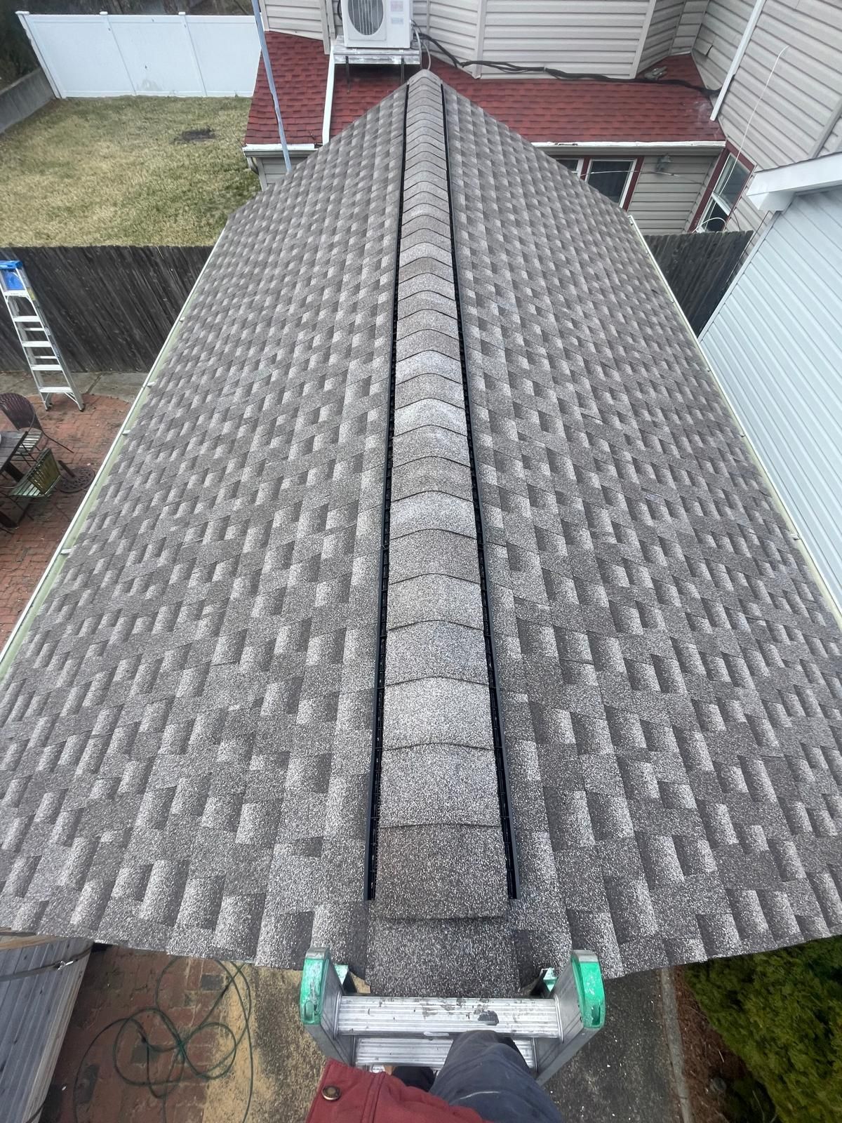 A person is standing on a ladder on top of a roof.