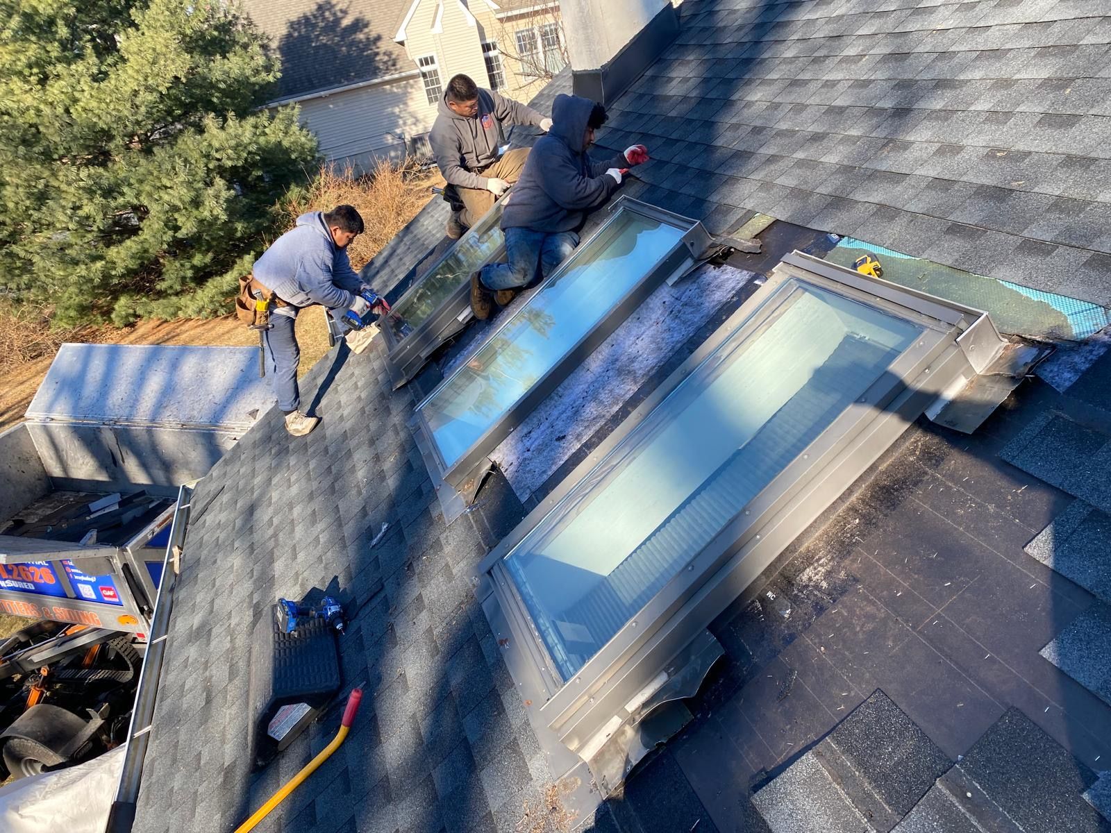 A group of men are working on the roof of a house.