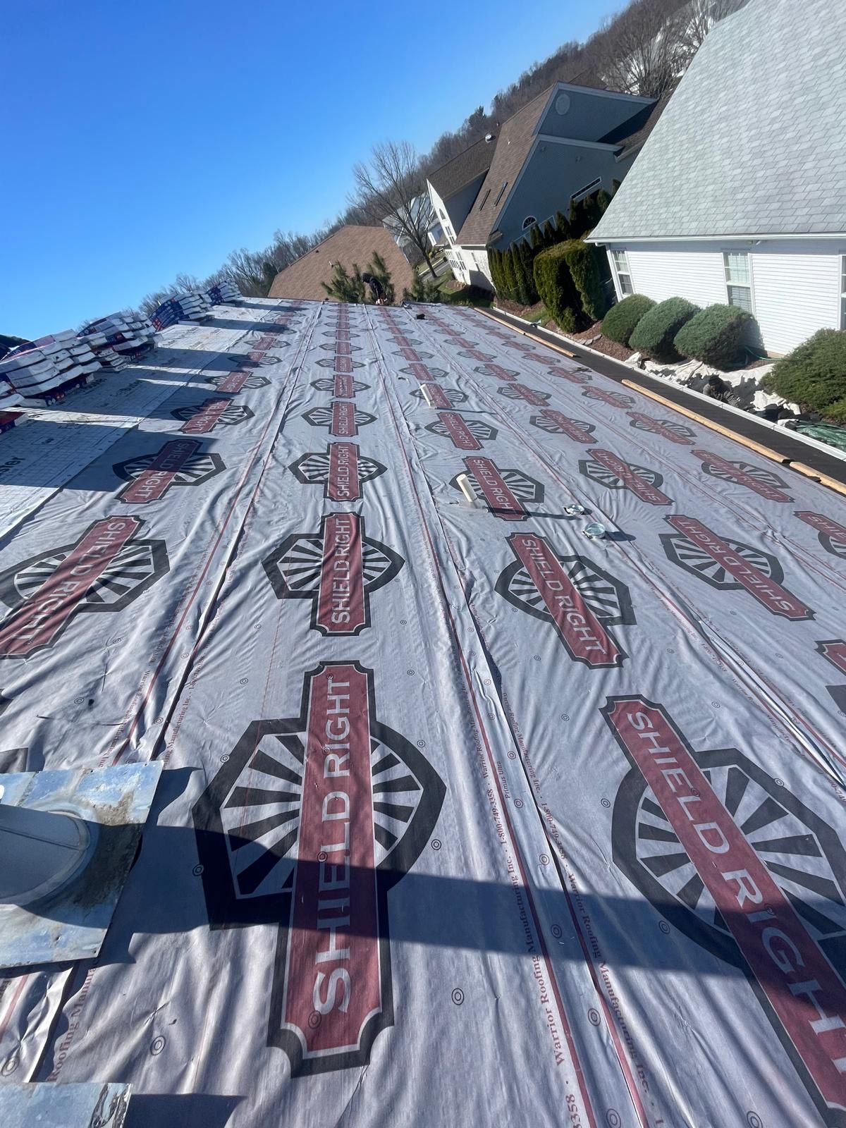 The roof of a house is being covered with a roofing material.