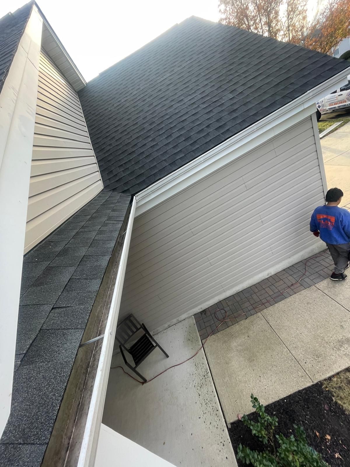 A man is standing on the side of a house with a black roof.