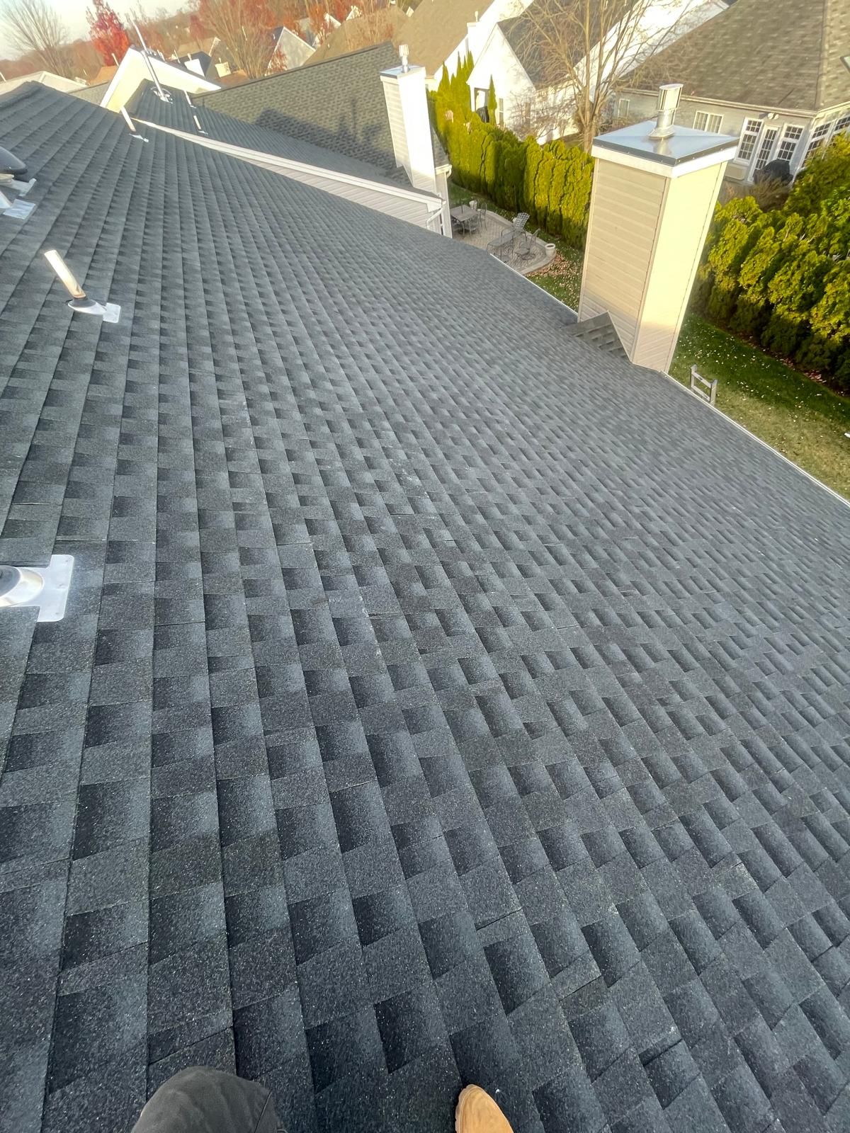 A person is standing on top of a black roof.