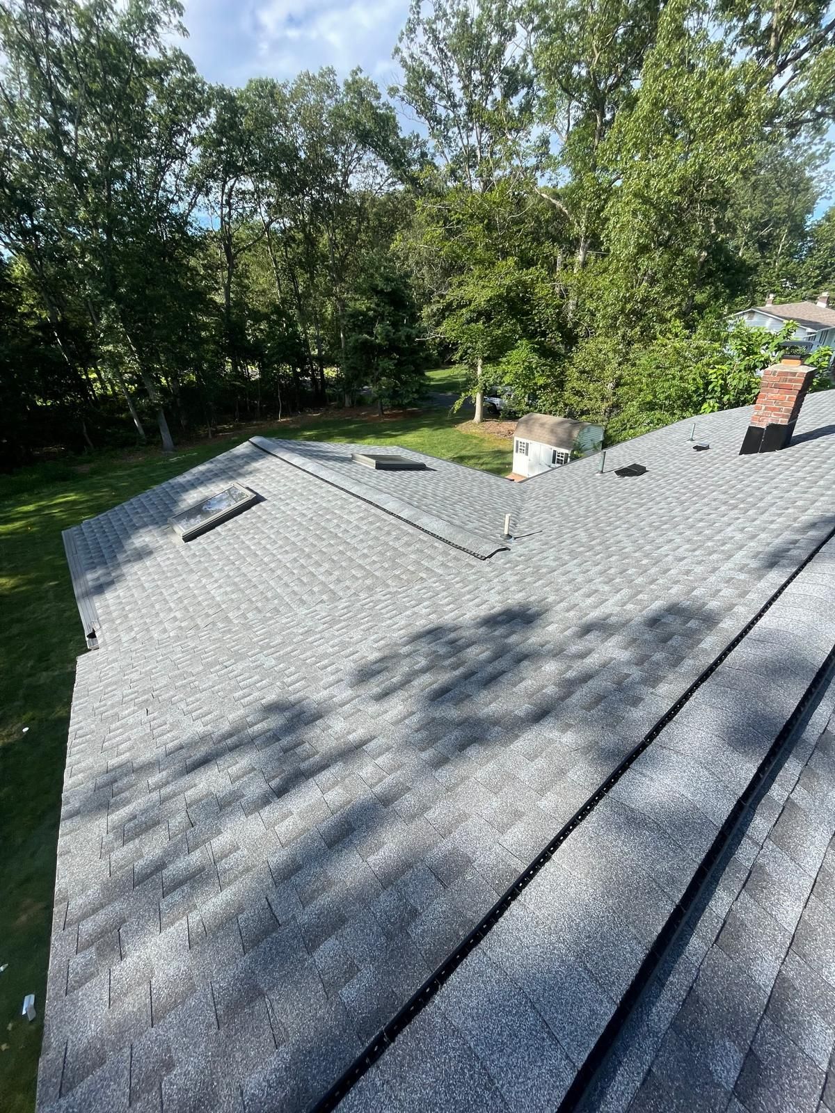 A roof with a lot of shingles on it and trees in the background.