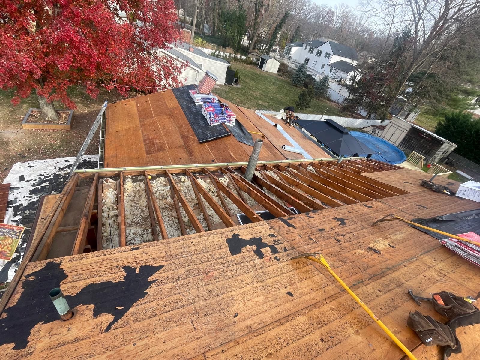 The roof of a house is being repaired and a tree is in the background.