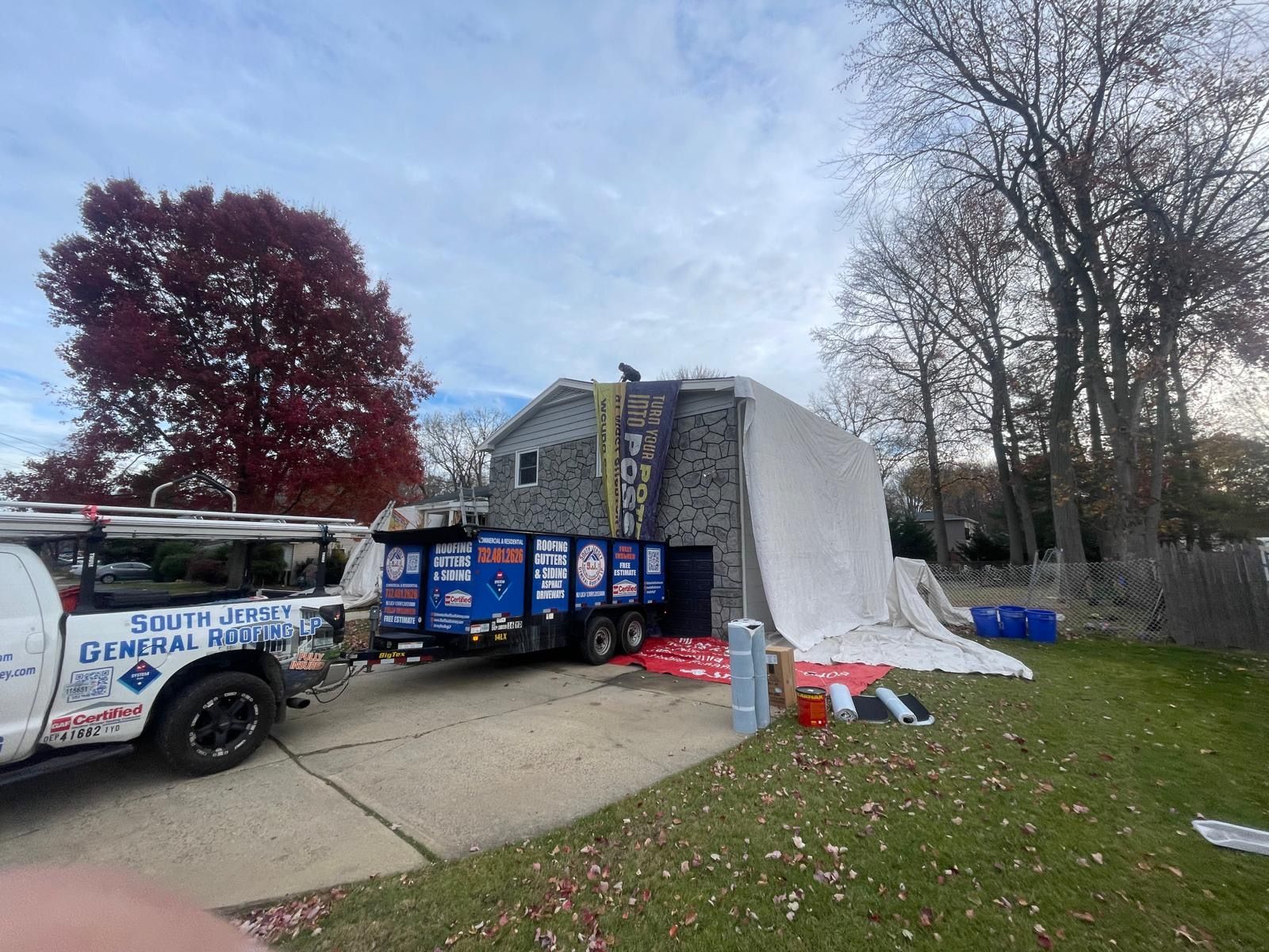 A truck is parked in front of a house with a tarp on it.