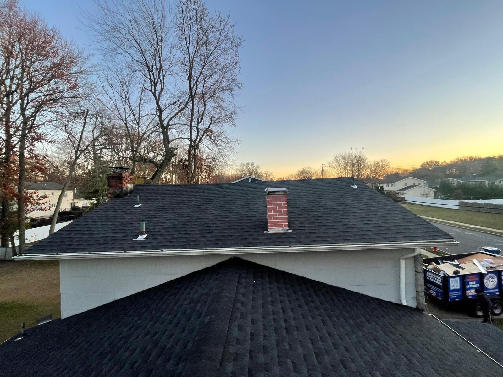 A house with a black roof and a chimney on top of it.