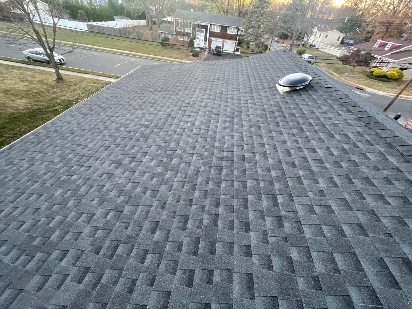 An aerial view of a roof with a house in the background.