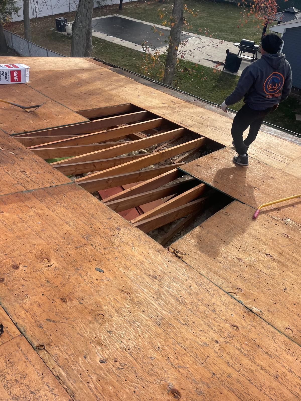 A man is standing on top of a wooden roof.