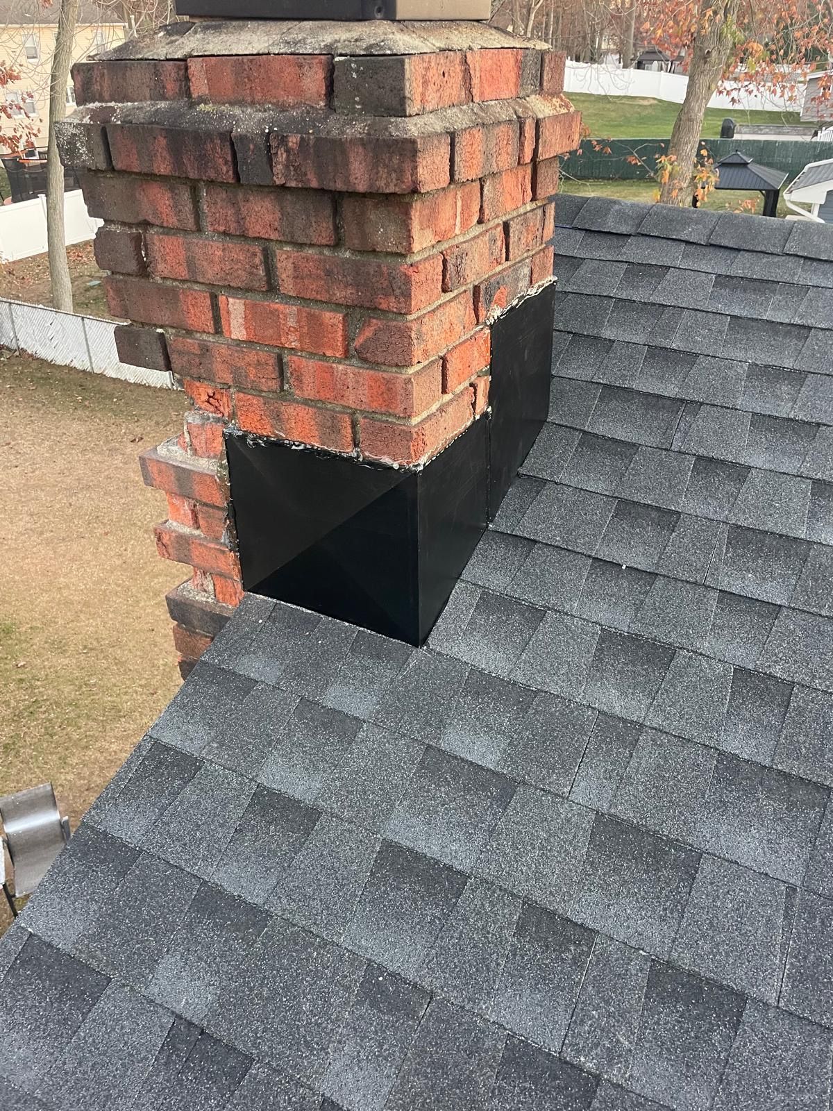 A brick chimney is sitting on top of a roof.