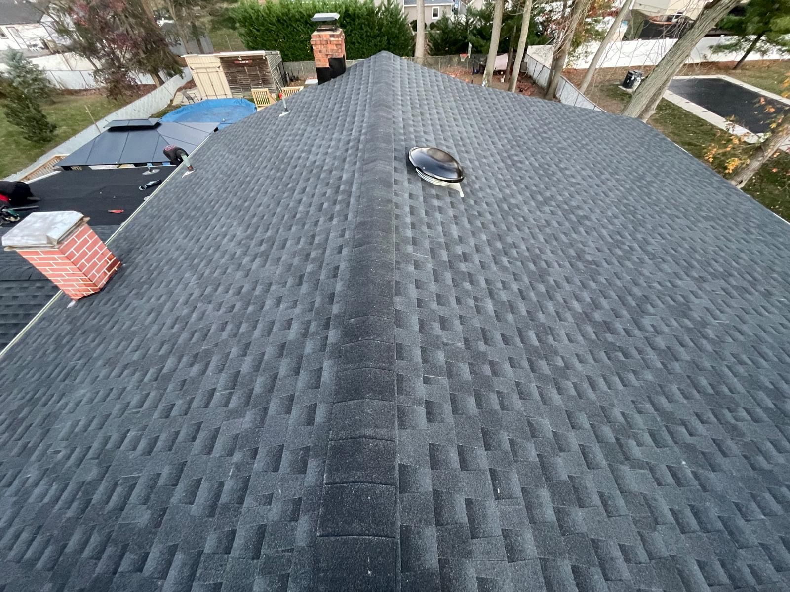 A roof with a chimney and a skylight on it.