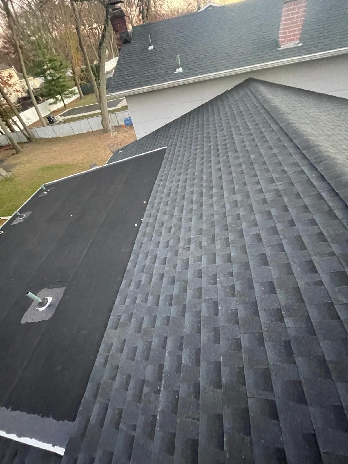 The roof of a house with a black roof and a chimney.