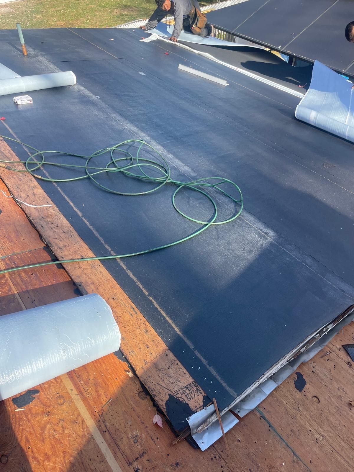 A person is working on a roof with a hose.