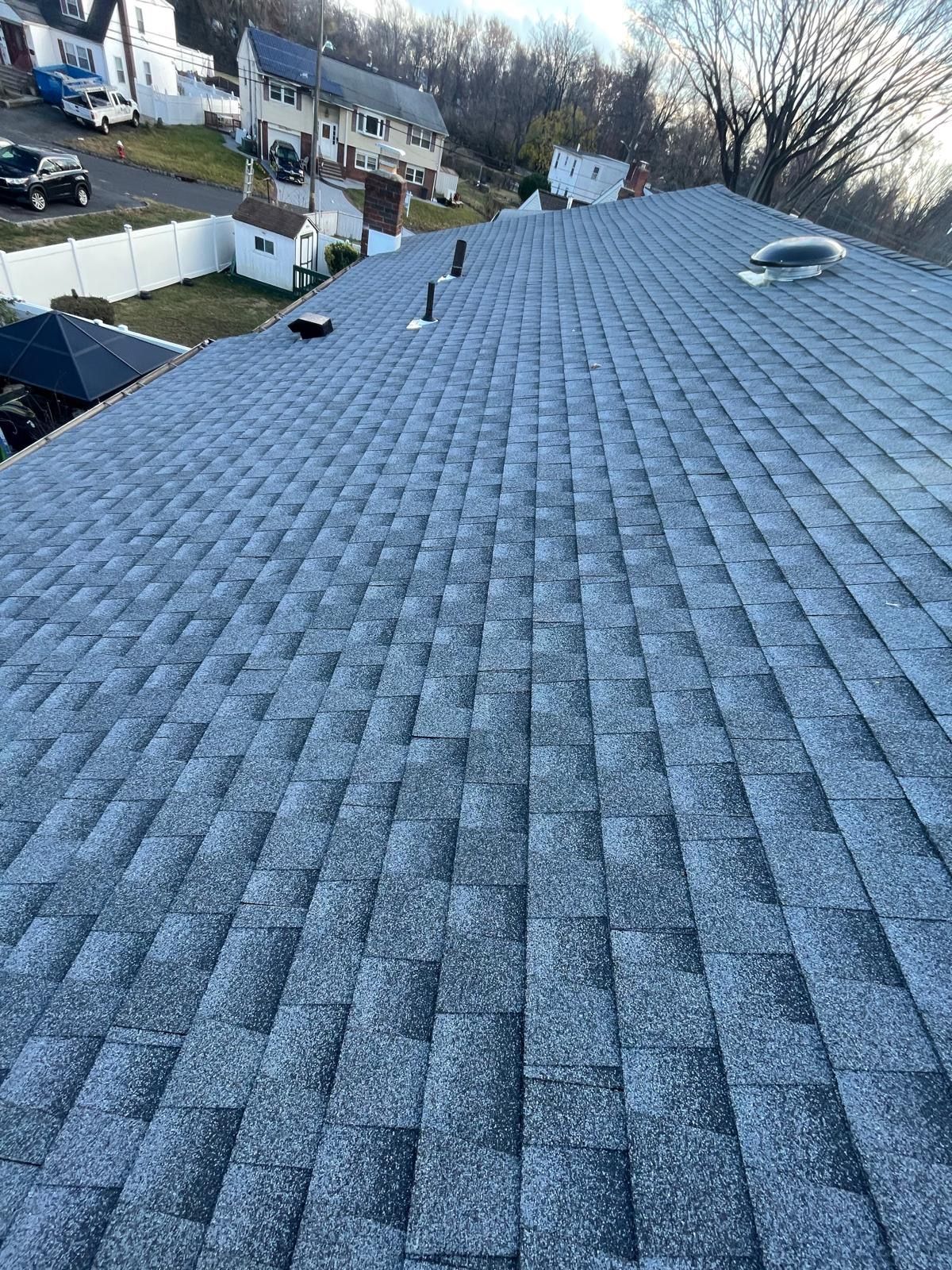 A roof with a lot of shingles and a skylight on it.