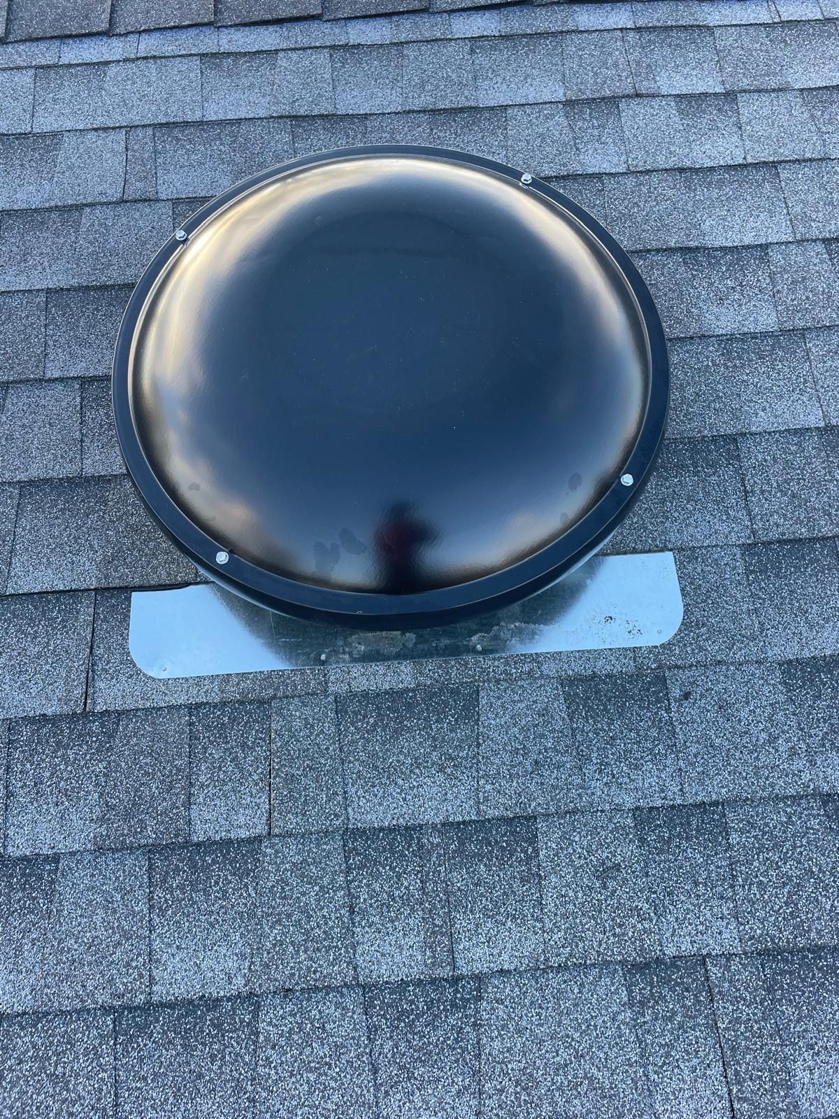 A round skylight is sitting on top of a roof.