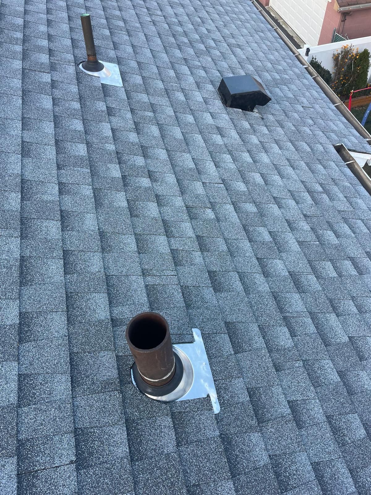 There are two chimneys on the roof of a house.